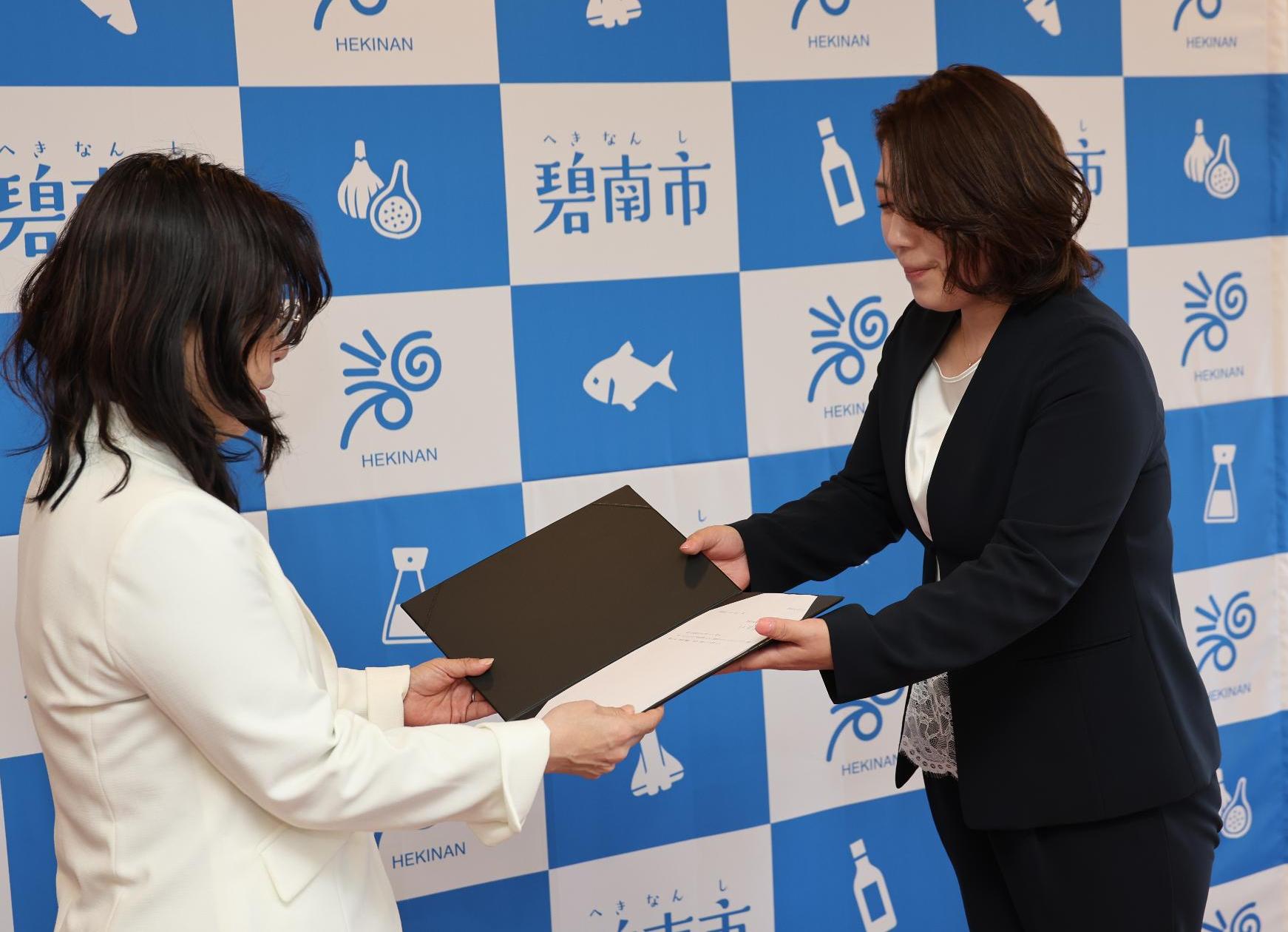 齊藤由里恵審議会会長（右）から小池友妃子市長（左）に答申書を手交する様子